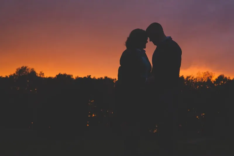 couple silhouetted at sunset in a field
