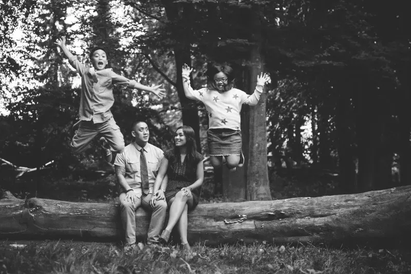 family in the woods with kids jumping behind their parents, black and white