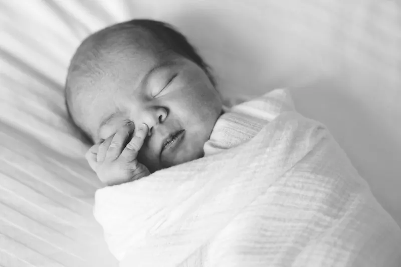 sleeping newborn swaddled in white, black and white