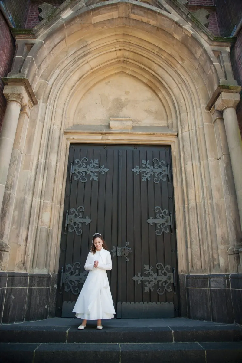 bride in a white dress in front of a gothic stone door