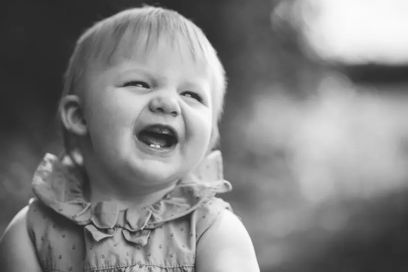 laughing toddler girl in a frilly dress, black and white