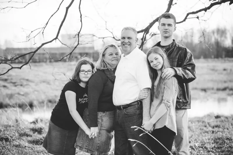 family of five in a field under bare winter branches, black and white