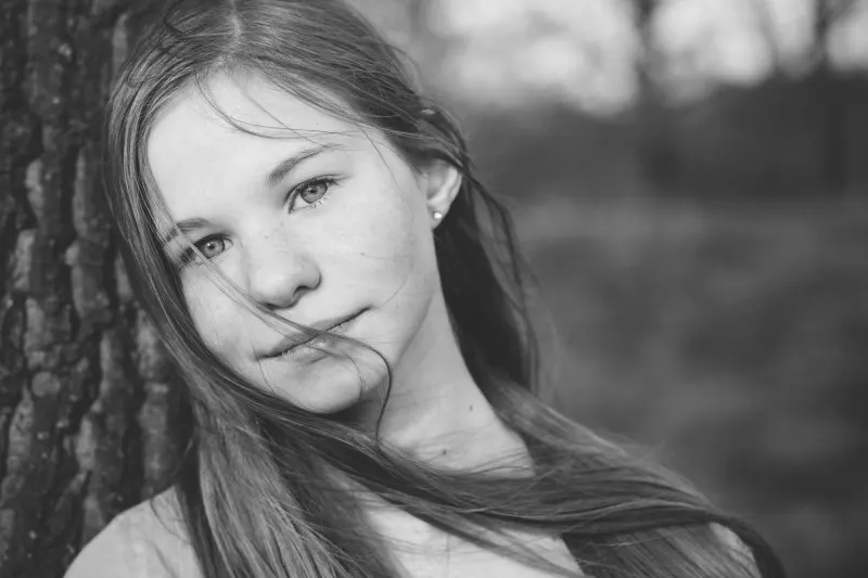 young woman leaning against a tree, black and white