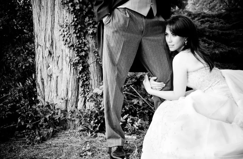 australian german wedding, bride sitting at the base of a tree holding her groom, black and white