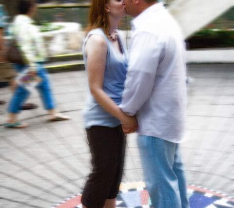 Newly engaged couple kissing face to face at the colorful WaterWorks park carousel plaza