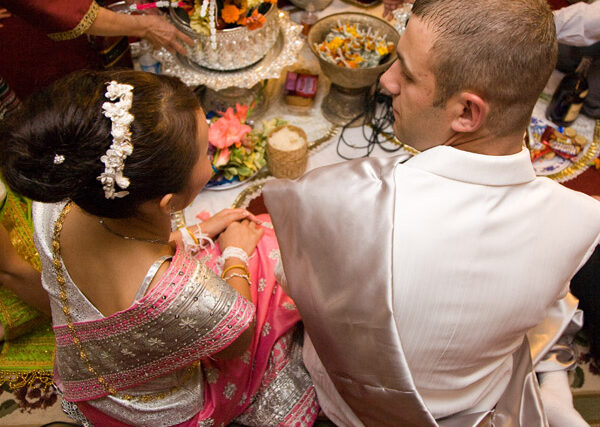 Newlywed couple in traditional Indian wedding attire at a decorated feast table