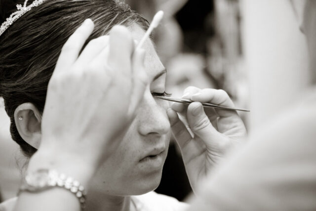 Close-up of a makeup artist applying eye makeup to a bride, black and white