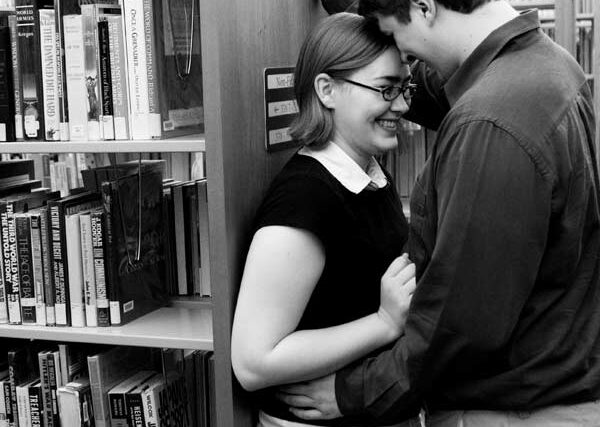 Couple embracing in a library bookstack aisle, black and white