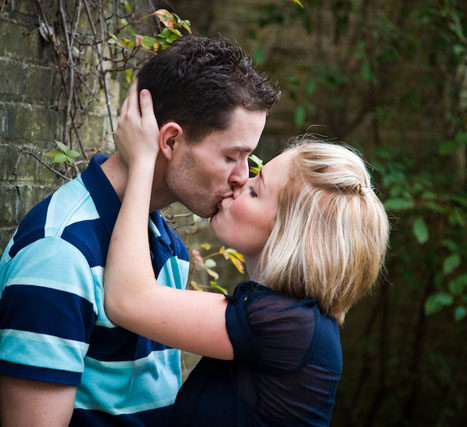 Woman with short blonde hair kissing her partner in a dimly lit room