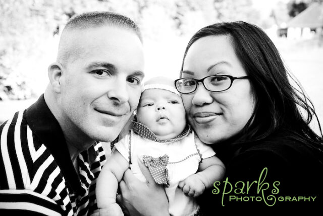 Young parents smiling with their infant daughter during a family portrait session