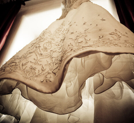 Lace wedding dress and veil hanging on a door with dramatic light