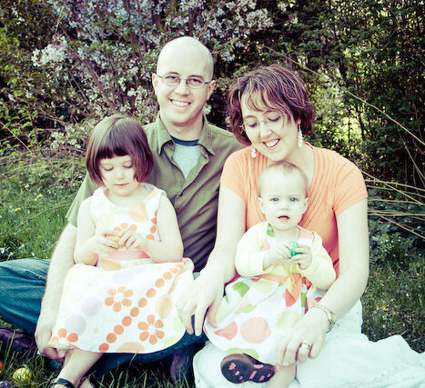 Multi-generation Easter family portrait, mother holding a baby, children in pastel clothes, grandmother posing outdoors