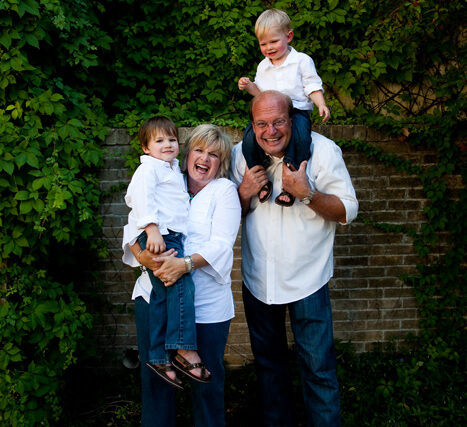 Father standing with his three children, a toddler on his shoulders, in the garden
