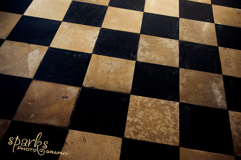 Weathered black and tan checkerboard tile floor in dramatic light