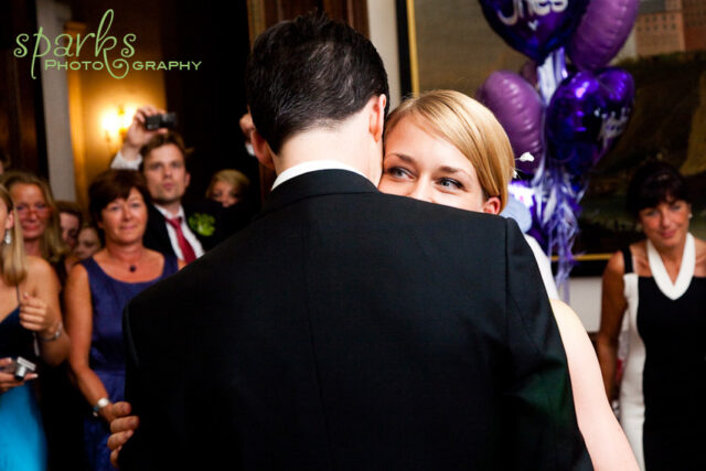 The bride and groom share an intimate moment during their wedding as guests look on.