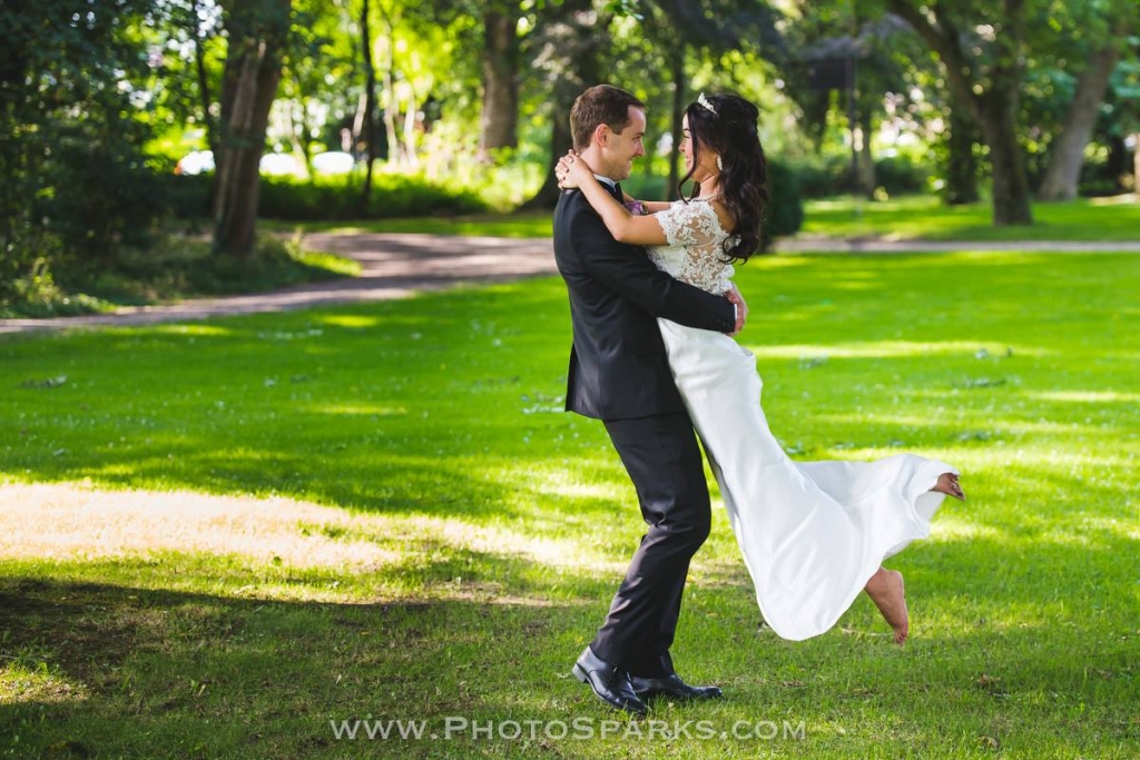 Groom dips his bride in a white dress during their wedding on a grassy lawn at Château St. Gerlach.