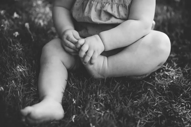 black and white portrait of a toddler sitting in the grass