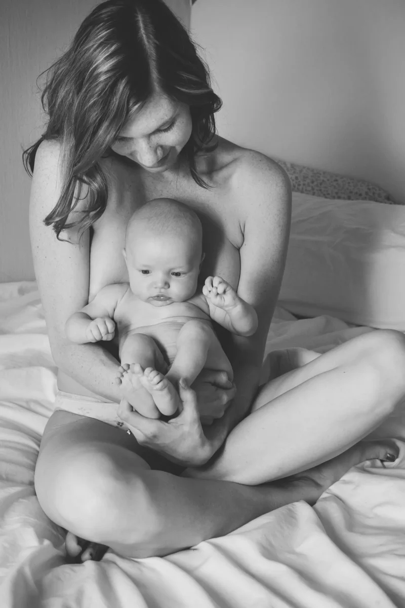 mother holding her newborn on the bed, black and white