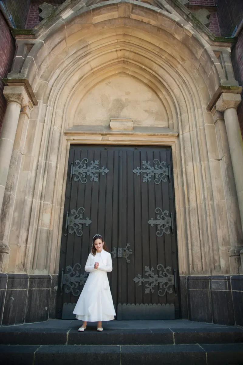 bride in a white dress in front of a gothic stone door