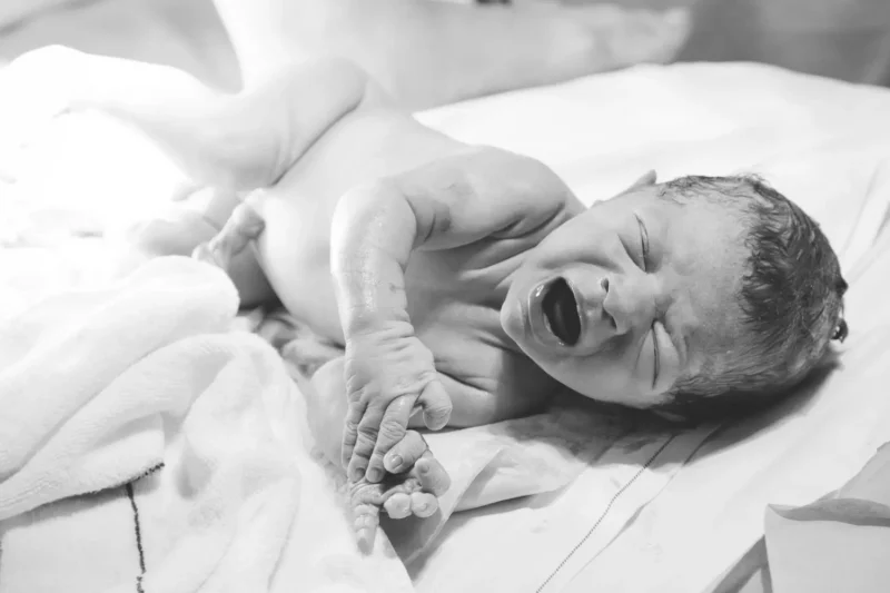 crying newborn lying on a towel, black and white