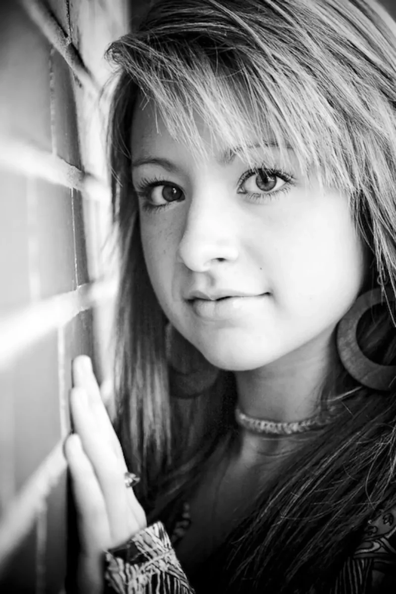 Black-and-white portrait of a girl looking over her shoulder at a bright window