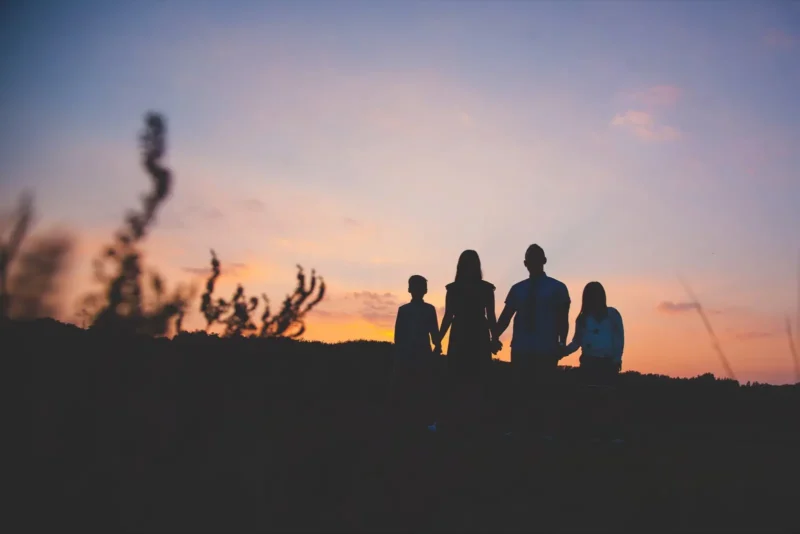 Silhouette of a family walking along a ridge against a purple sunset