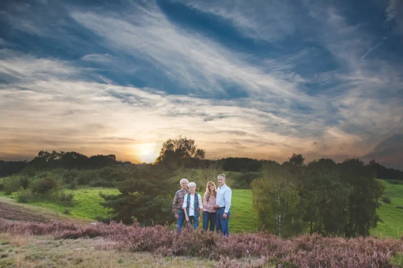 Family of four standing on a heather field overlooking a setting sun