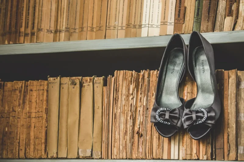 Pair of embellished ballet-flat wedding shoes resting on a shelf of aged books