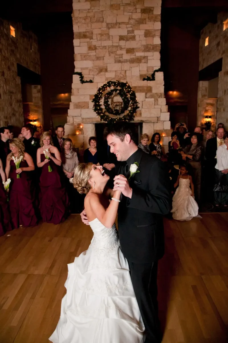 Newlyweds slow dancing in a stone hall before a wreath-adorned column